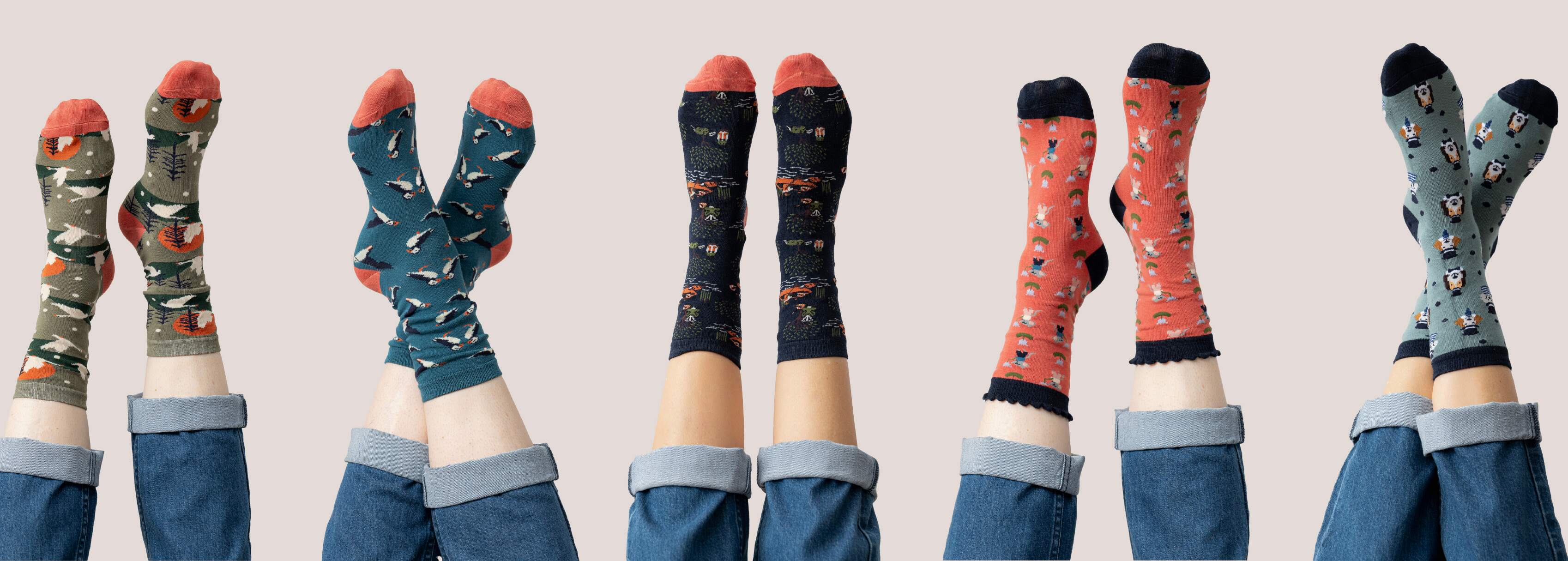 Colourful patterned socks in a 3 for 2 discount worn with jeans on a plain background